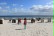 Man sieht den Strand mit einigen Strandkörbe. Im Hintergrund kann man das Meer sehen. Die Kinder laufen durcheinander.
